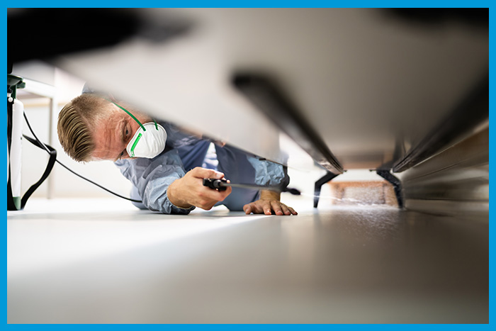 Exterminateur cherchant des nuisibles sous un meuble