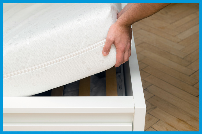 Homme inspectant le sommier à la recherche de punaises de lit